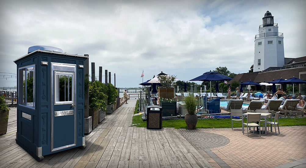 Security Booth | The Guard Post 16 with a navy color, on a boardwalk near a seaside pool with a lighthouse in the distance.