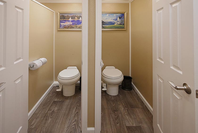 FULLY ENCLOSED BATHROOM STALLS WITH FLOOR TO CEILING LOCKABLE WOOD DOORS FOR COMPLETE PRIVACY